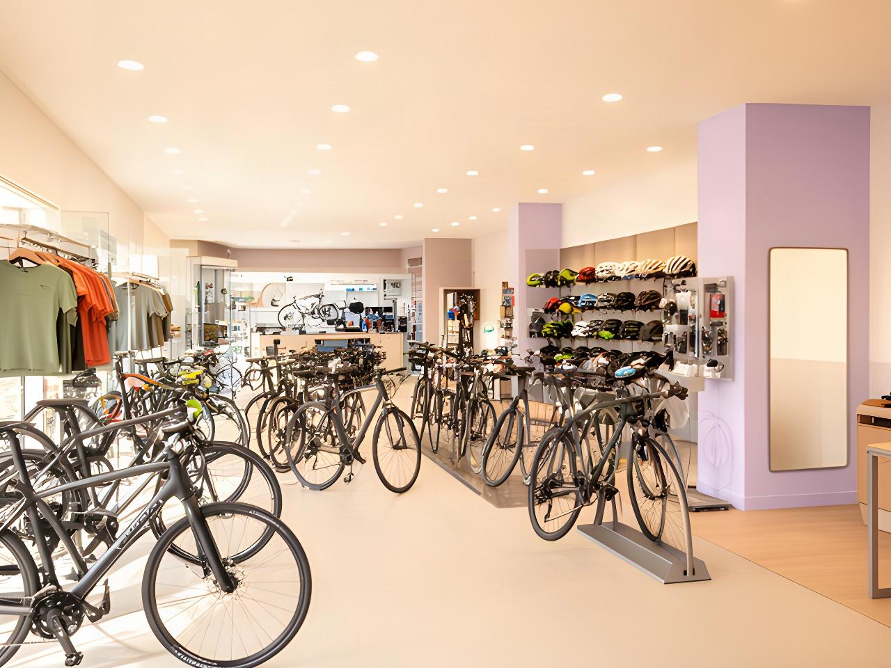 Helle Verkaufsfläche von Müller & Meier Velo mit Fahrradbekleidung, Helmen und einer sichtbaren modernen Werkstatt